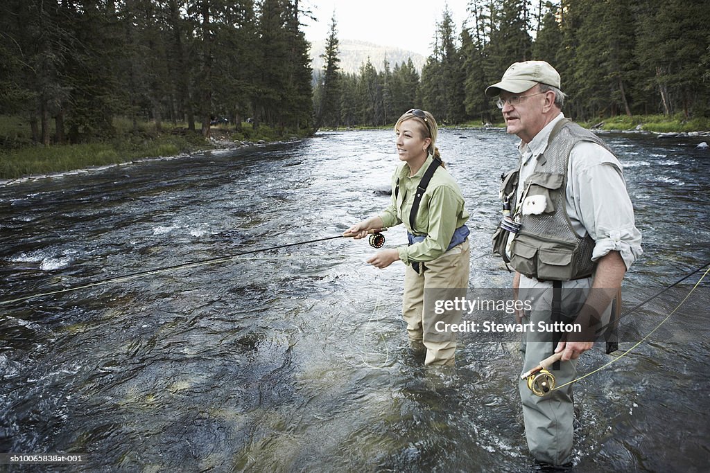 Senior man teaching woman fly-fishing