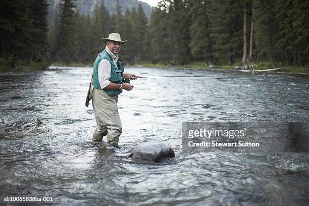 portrait of senior man flyfishing in river - fly fishing foto e immagini stock