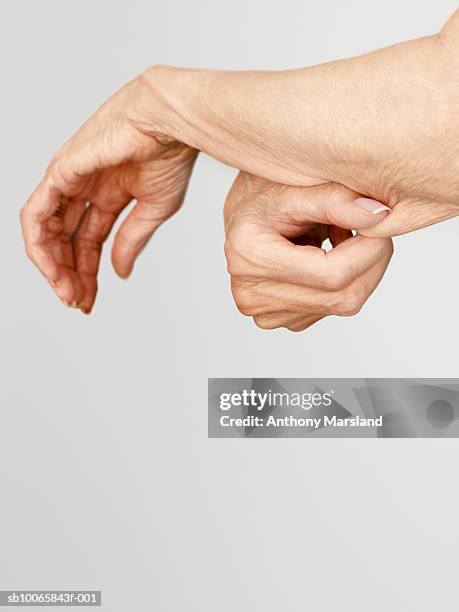 woman pinching skin on arm, close-up - aging skin stock-fotos und bilder