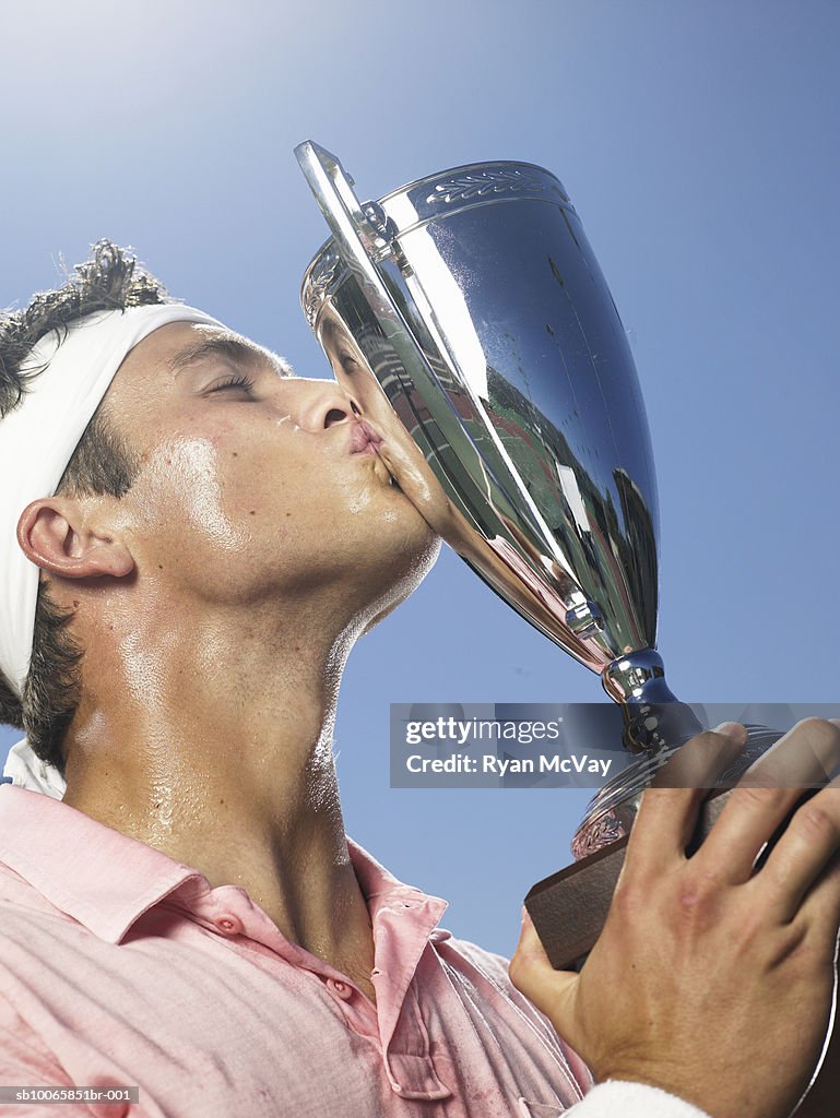Young man kissing tennis trophy
