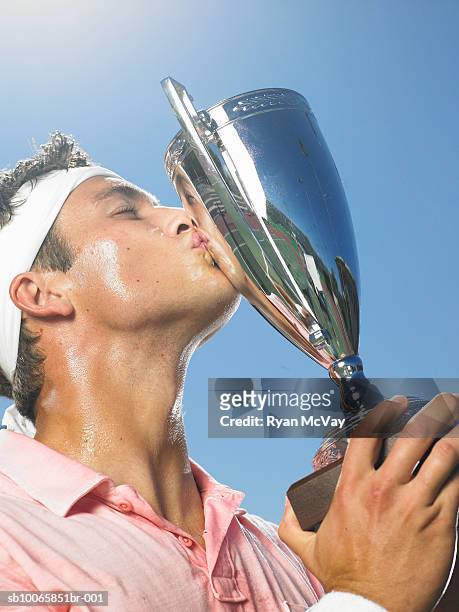 young man kissing tennis trophy - sports trophy stock pictures, royalty-free photos & images