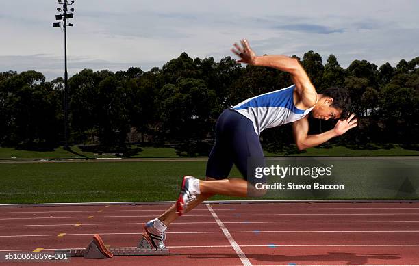 male athlete running from starting block on track - mens track photos et images de collection