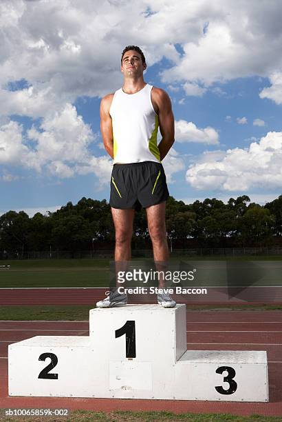male athlete on winners podium on track - winners podium stock pictures, royalty-free photos & images