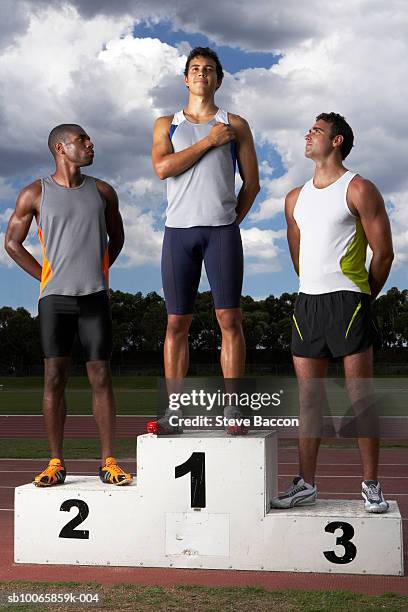 male athletes looking at winner on podium beside track - prispall bildbanksfoton och bilder