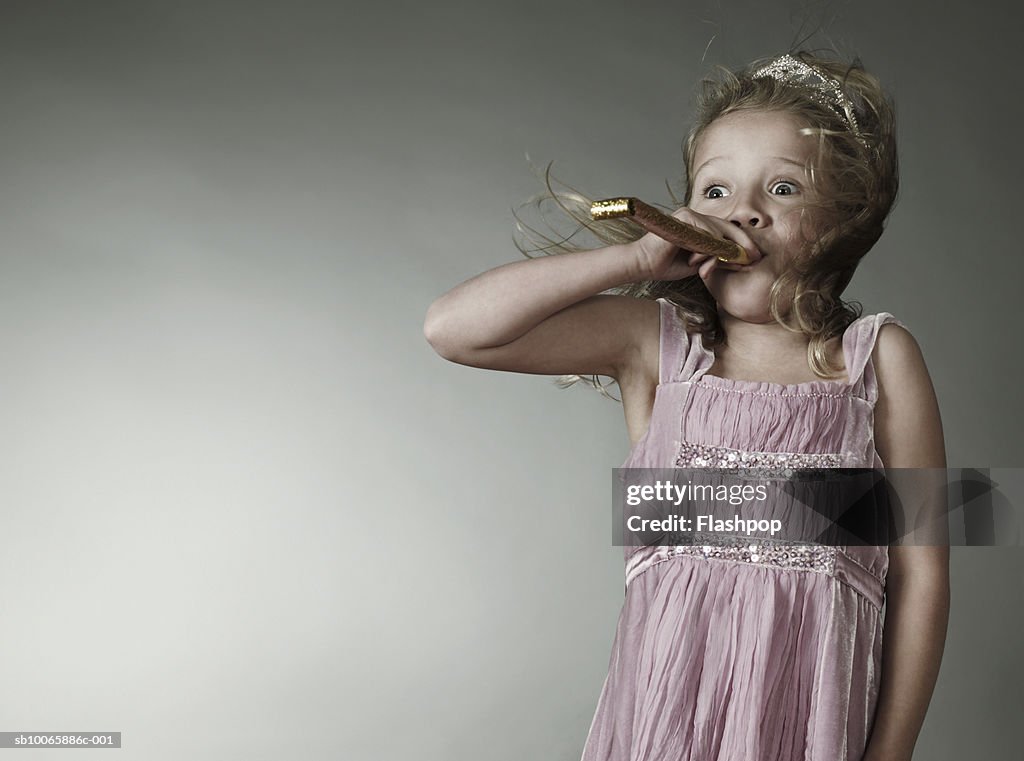 Girl (6-7) blowing party blower