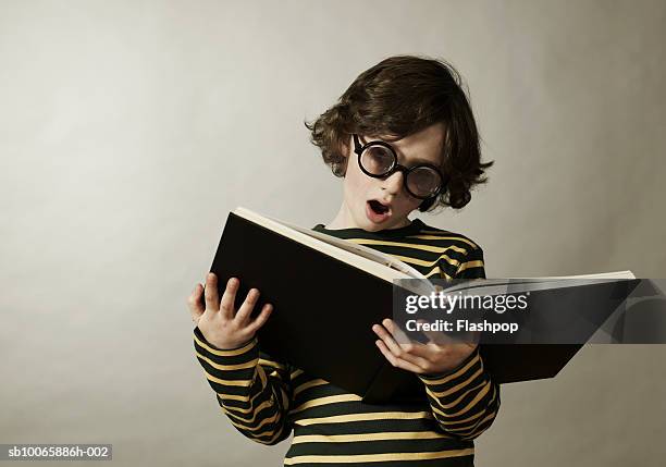 boy (8-9) reading book, mouth open - reading glasses - fotografias e filmes do acervo