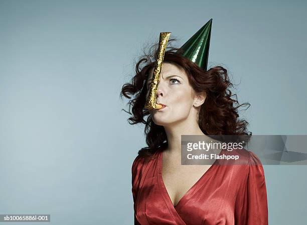 woman wearing party hat, blowing party blower - matasuegras fotografías e imágenes de stock