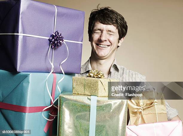 man with gift boxes, eyes closed, smiling - excess photos et images de collection