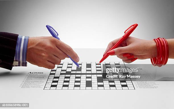man and woman doing crossword, close-up of hands - korsord bildbanksfoton och bilder