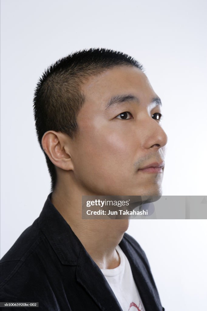 Man standing against white background, looking away, close-up