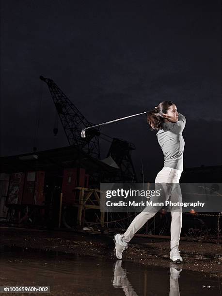young woman playing golf in street - golfswing stock pictures, royalty-free photos & images