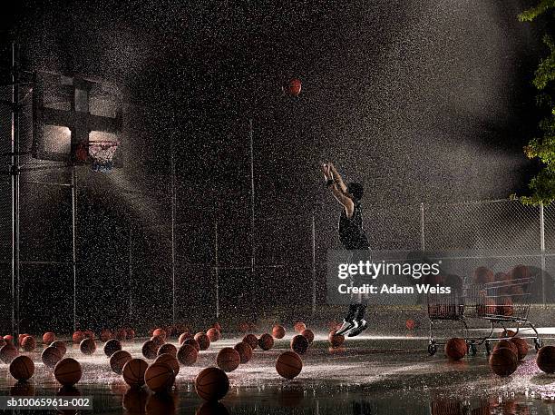 man shooting basketball at night in rain, side view - decision fotografías e imágenes de stock