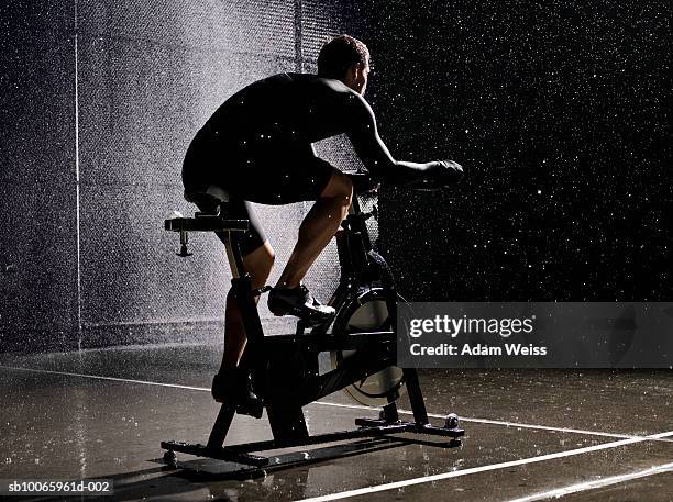 man using exercise bike in basketball court at night - peloton stock pictures, royalty-free photos & images