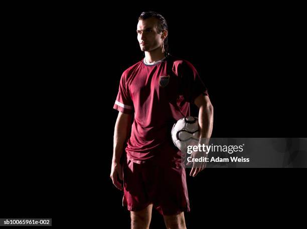 man holding football under arm, looking away - tenue de football photos et images de collection