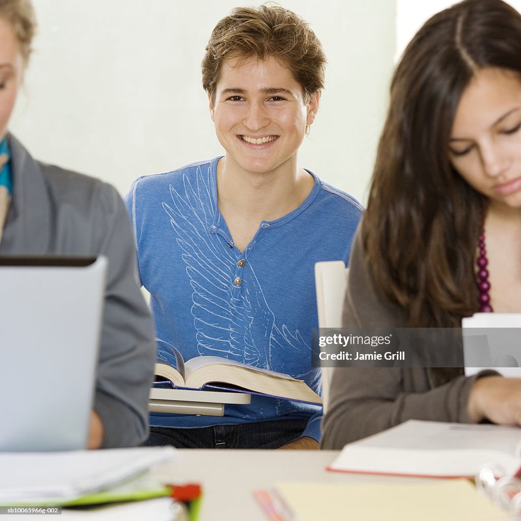 Young man in class, smiling (focus on background)
