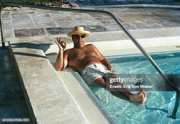 man lying in swimming pool, portrait - bermuda shorts stock pictures, royalty-free photos & images