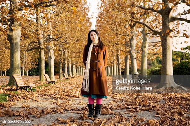 young woman standing between row of trees in autumn - 若い女性一人 ストックフォトと画像