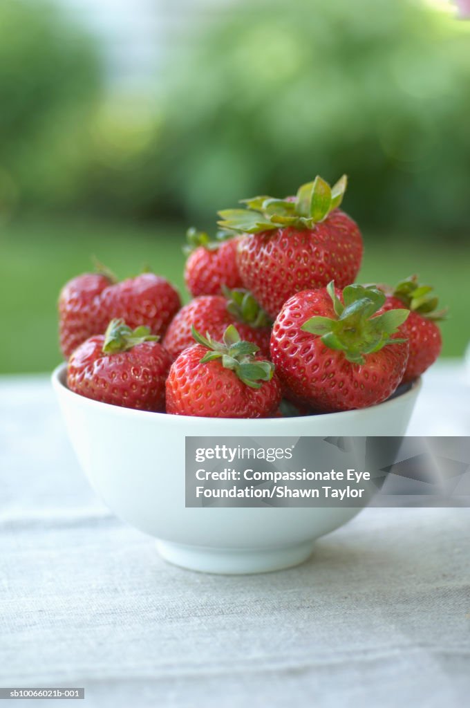 Bowl of strawberries on table outdoors