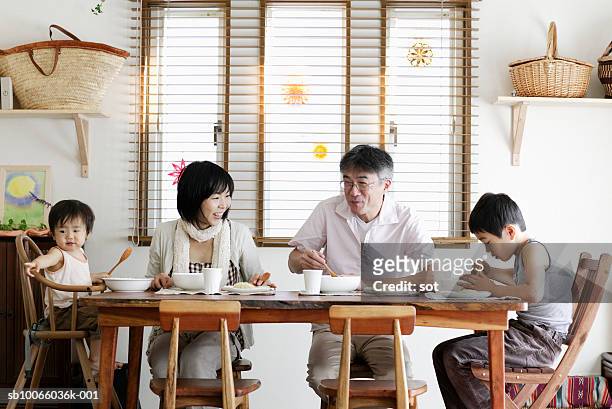 couple with son (8-9 years) and baby boy (18-24 months) eating at dining table - older mother baby 40 years foto e immagini stock