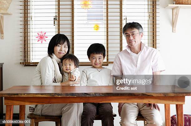 couple with son (8-9 years) and baby boy (18-24 months) sitting at dining table, portrait - older mother baby 40 years foto e immagini stock