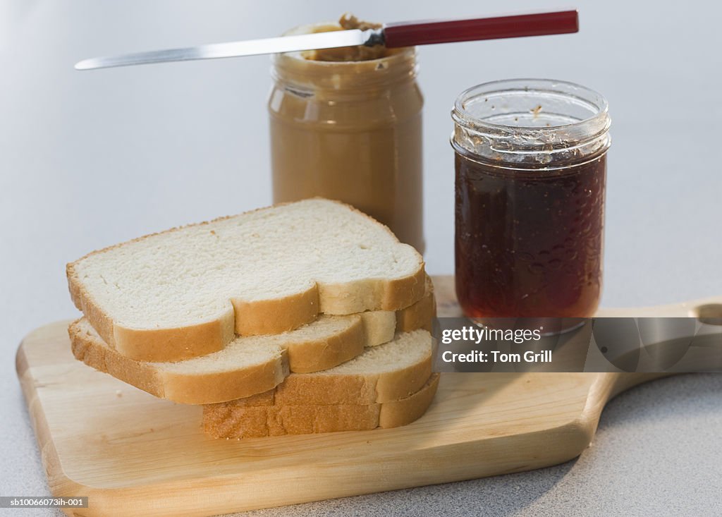Bread slices with peanut butter and jelly on chopping board, close-up