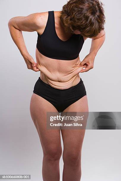 woman holding skin of waist - flácido imagens e fotografias de stock