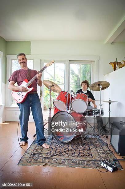 father and son (14-15) playing guitar and drums, smiling - vater sohn musik stock-fotos und bilder
