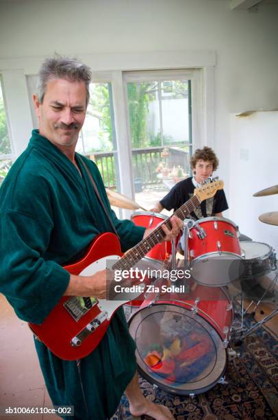 father and son (14-15) playing guitar and drums - robe stock pictures, royalty-free photos & images