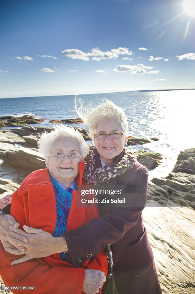 Two women standing at beach, smiling, portrait