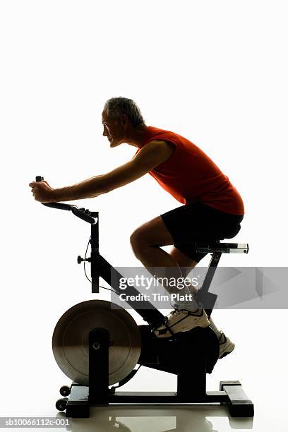 mature man working out on exercise bike, side view - pinning foto e immagini stock