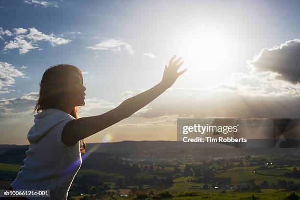 young woman reaching her hand to sun, dusk - hands sun stock-fotos und bilder
