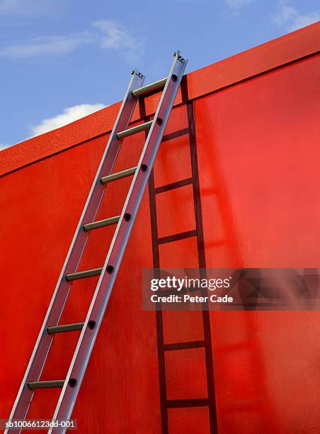 step ladder leaning up against red wall - scala a pioli foto e immagini stock