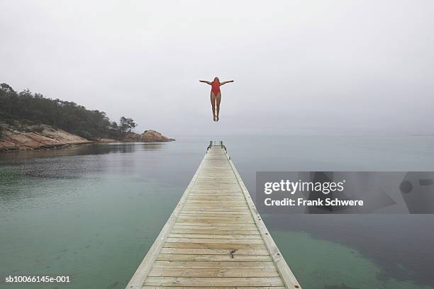 woman diving off jetty, arms outstretched - floating piers ストックフォトと画像