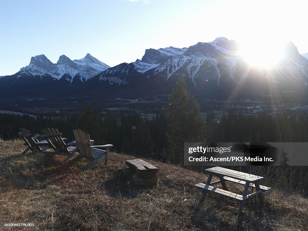 Armchair and table on hill in front of snowcapped mountain, dusk