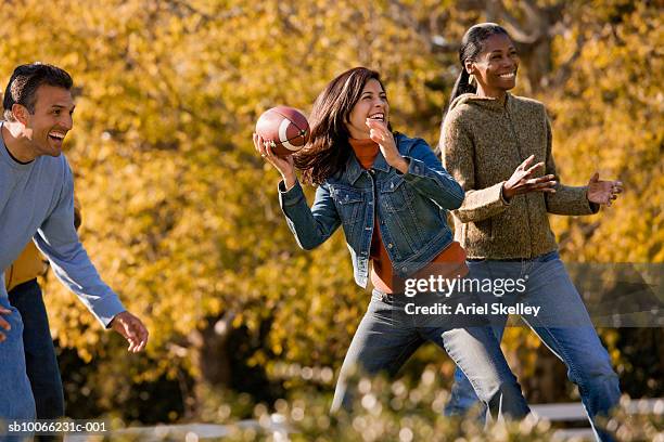 mature man and women playing american football in park, smiling - throwing football stock pictures, royalty-free photos & images