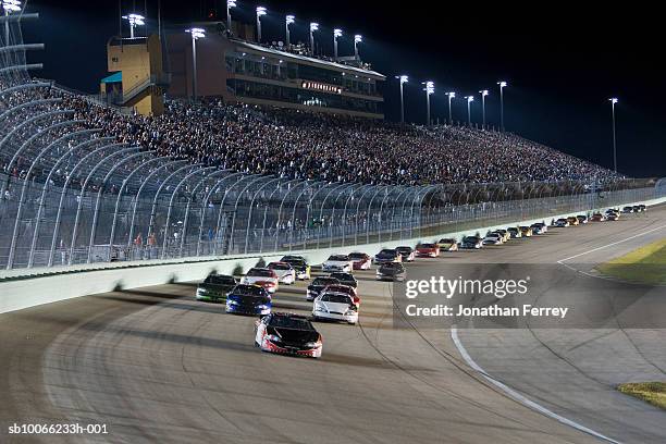stock cars racing around track at night (blurred motion) - circuit automobile photos et images de collection