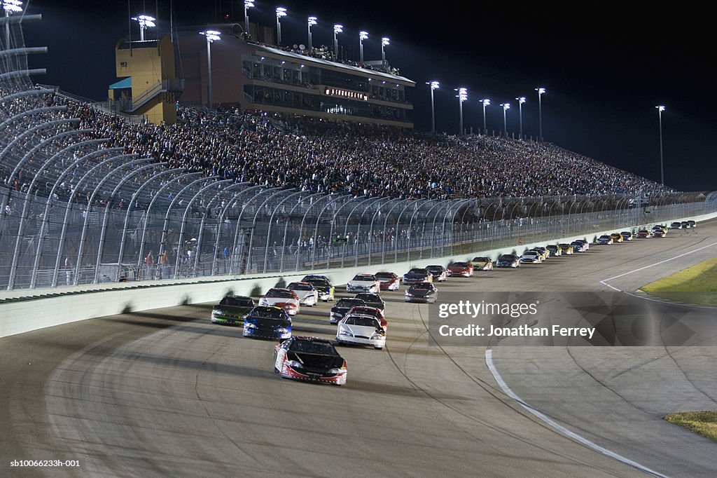 Stock cars racing around track at night (blurred motion)