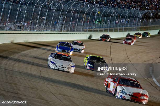stock cars racing around track at night (blurred motion) - stock car racing stock-fotos und bilder