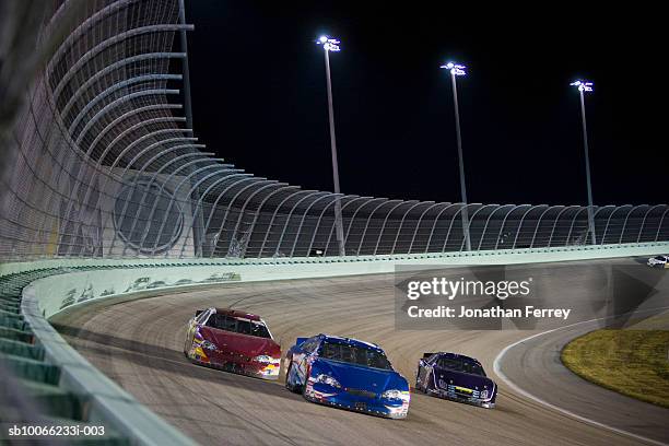 stock cars racing around track at night (blurred motion) - stock car racing stock-fotos und bilder