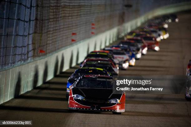 stock cars racing around track at night - nascar track stock pictures, royalty-free photos & images