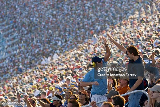 crowd in stadium watching stock car racing, two men having high-five - sports car photos et images de collection