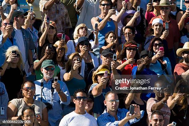 crowd in stadium watching car racing, photographing with mobile phones (full frame) - holding aloft stock pictures, royalty-free photos & images