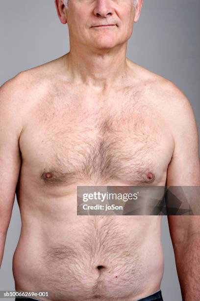 barechested man standing against grey background, close-up, mid section - behaart stock-fotos und bilder