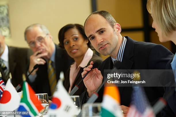 business executives at conference table, focus on man - international flags stock-fotos und bilder