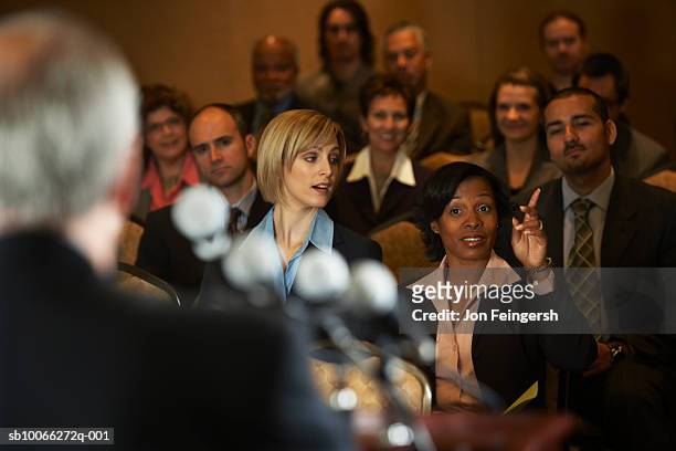 business executives at conference room, focus on woman with hand raised - conferenza stampa foto e immagini stock