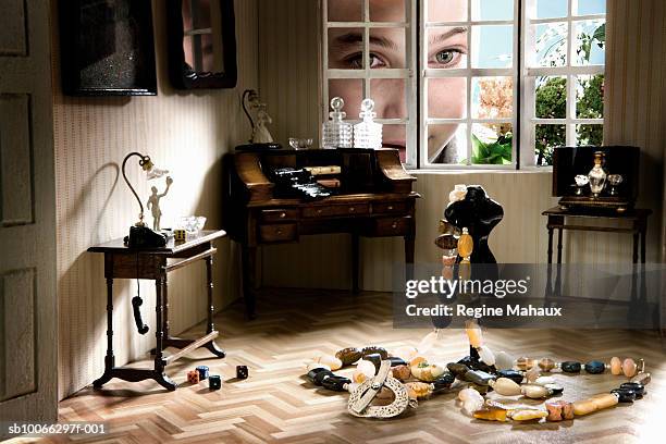 girl (6-7 years) looking into doll house through miniature window, close up - looking through a doll house stock-fotos und bilder