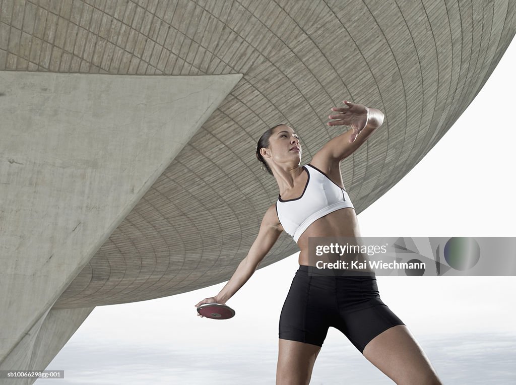 Young woman throwing discus at stadium