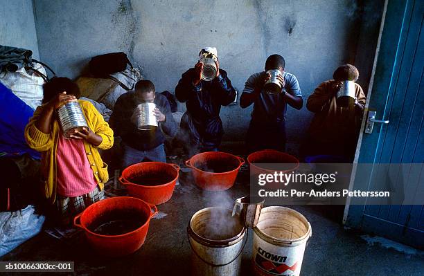 south africa, cape town, khayelitsha, people drinking herbal medicine from cans at traditional doctor's house - khayelitsha foto e immagini stock