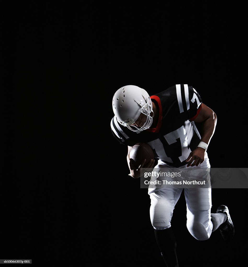 American football player kneeling on black background
