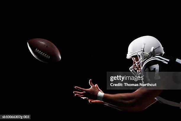 american football player catching ball, side view - futbol americano fotografías e imágenes de stock